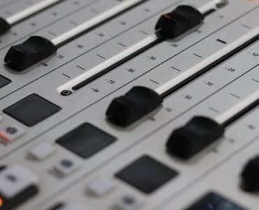 Close-up view of a professional audio mixer with sliders and control knobs, ideal for sound production.