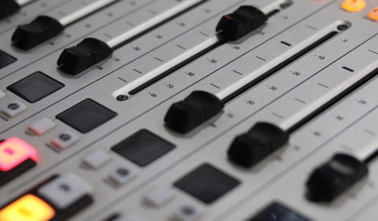 Close-up view of a professional audio mixer with sliders and control knobs, ideal for sound production.